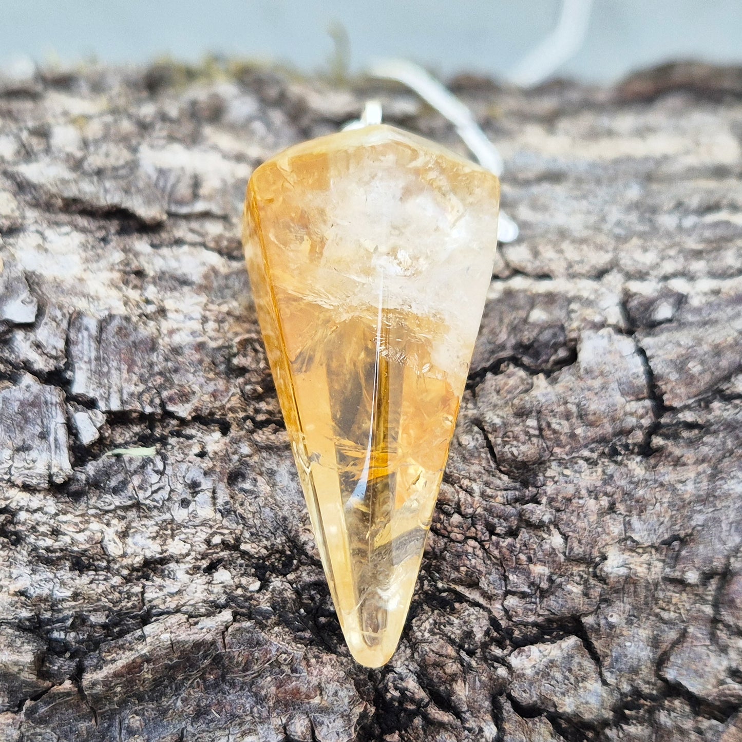 Citrine Crystal Pendulum from Brazil. This stunning sunny pendulum carrys the warm, golden glow Citrine is loved for. It has a yellow bead at the end of the chain making it comfortable to hold and easy to use.