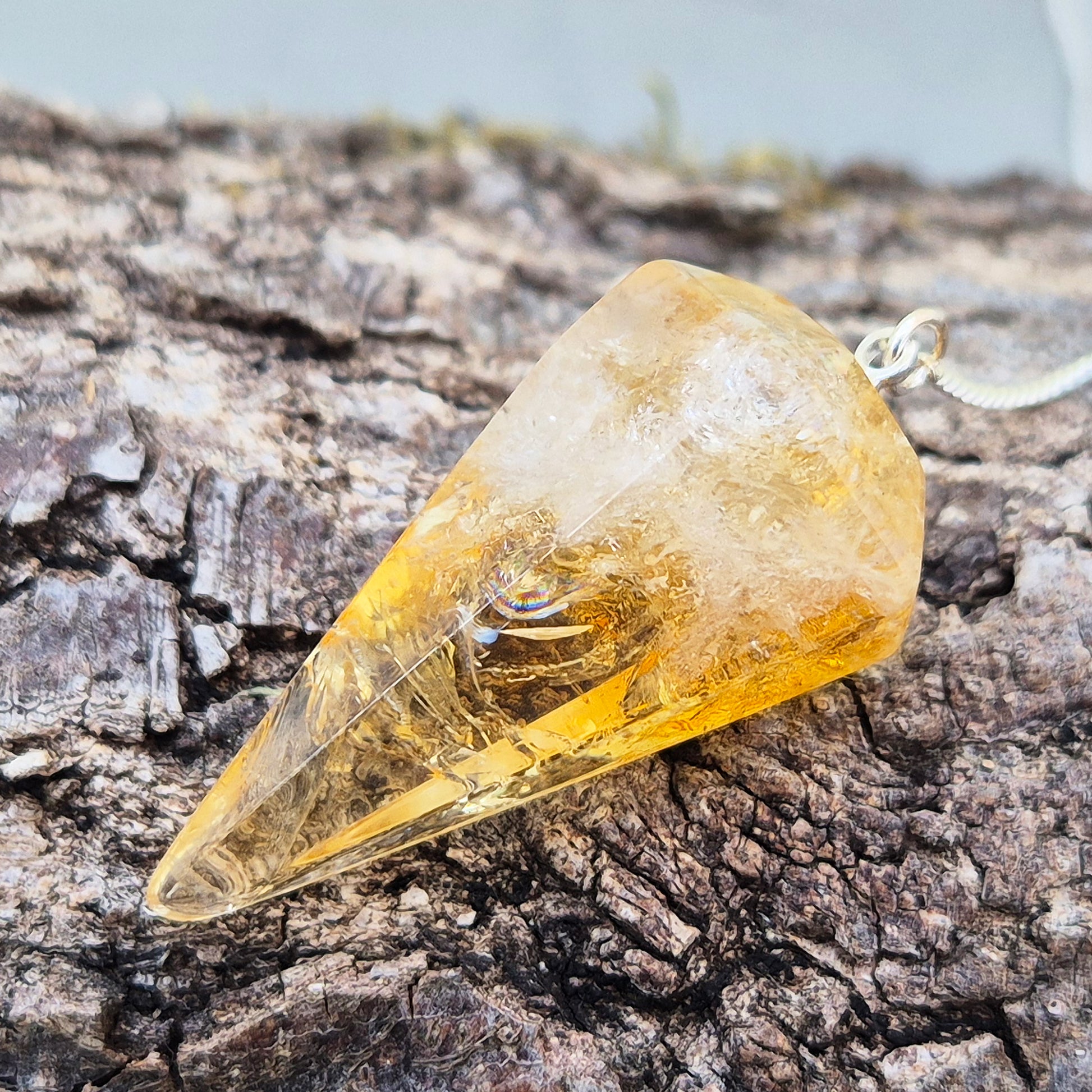 Citrine Crystal Pendulum from Brazil. This stunning sunny pendulum carrys the warm, golden glow Citrine is loved for. It has a yellow bead at the end of the chain making it comfortable to hold and easy to use.