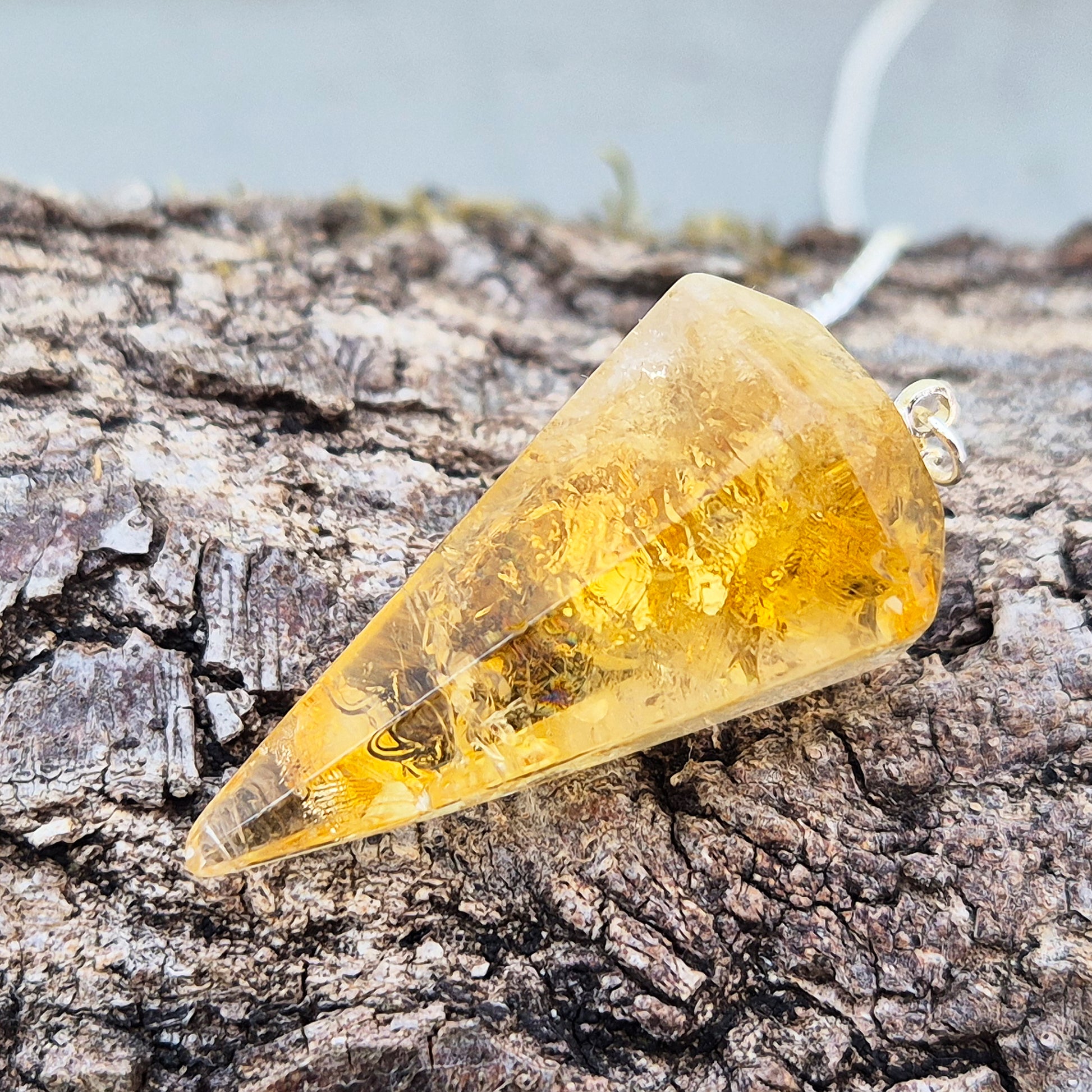 Citrine Crystal Pendulum from Brazil. This stunning sunny pendulum carrys the warm, golden glow Citrine is loved for. It has a yellow bead at the end of the chain making it comfortable to hold and easy to use.