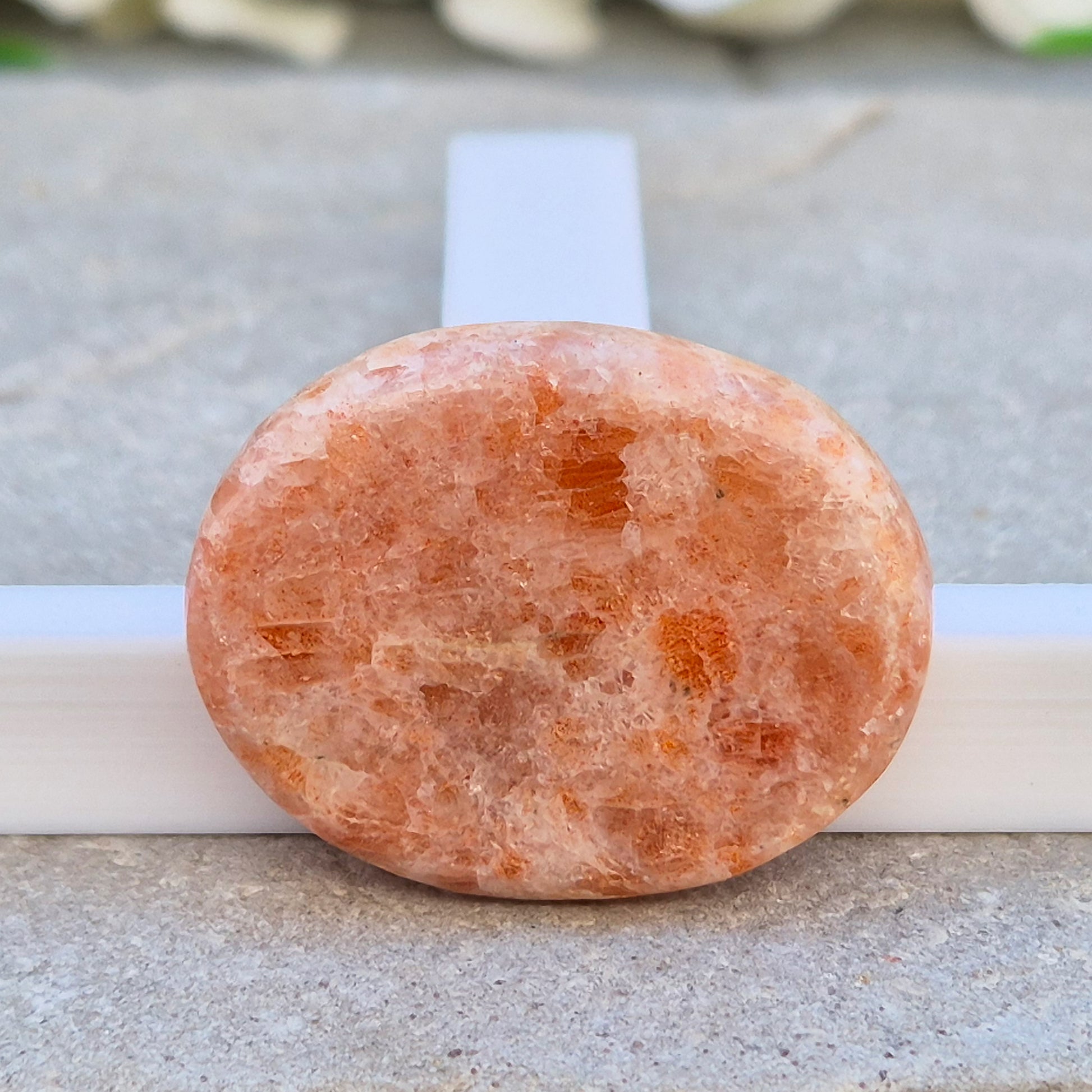 This flat, oval Sunstone palm stone carries soft peachy-orange tones and sits smoothly in the hand. Small enough to slip into a pocket or bag — sunshine you can carry with you.