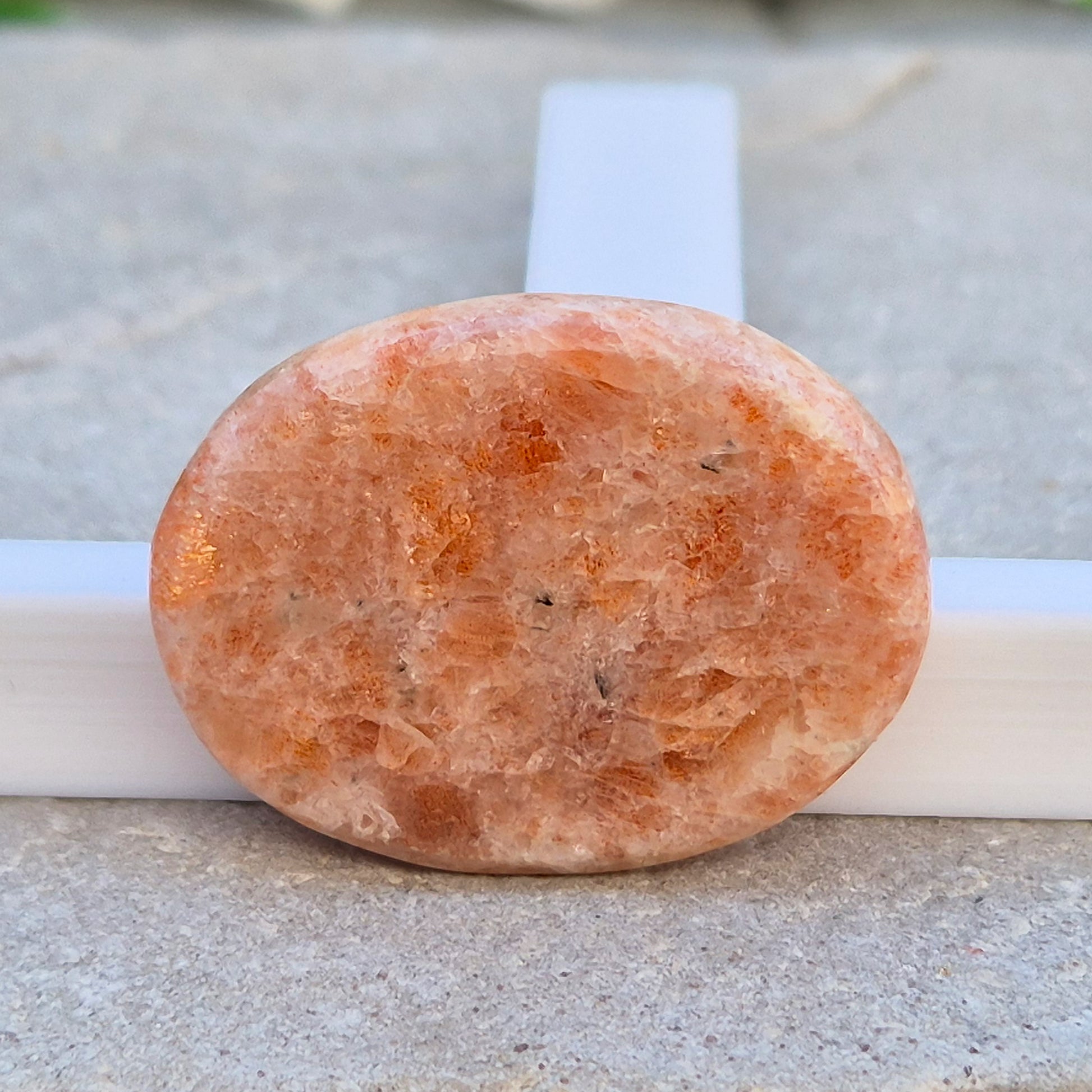 This flat, oval Sunstone palm stone carries soft peachy-orange tones and sits smoothly in the hand. Small enough to slip into a pocket or bag — sunshine you can carry with you.