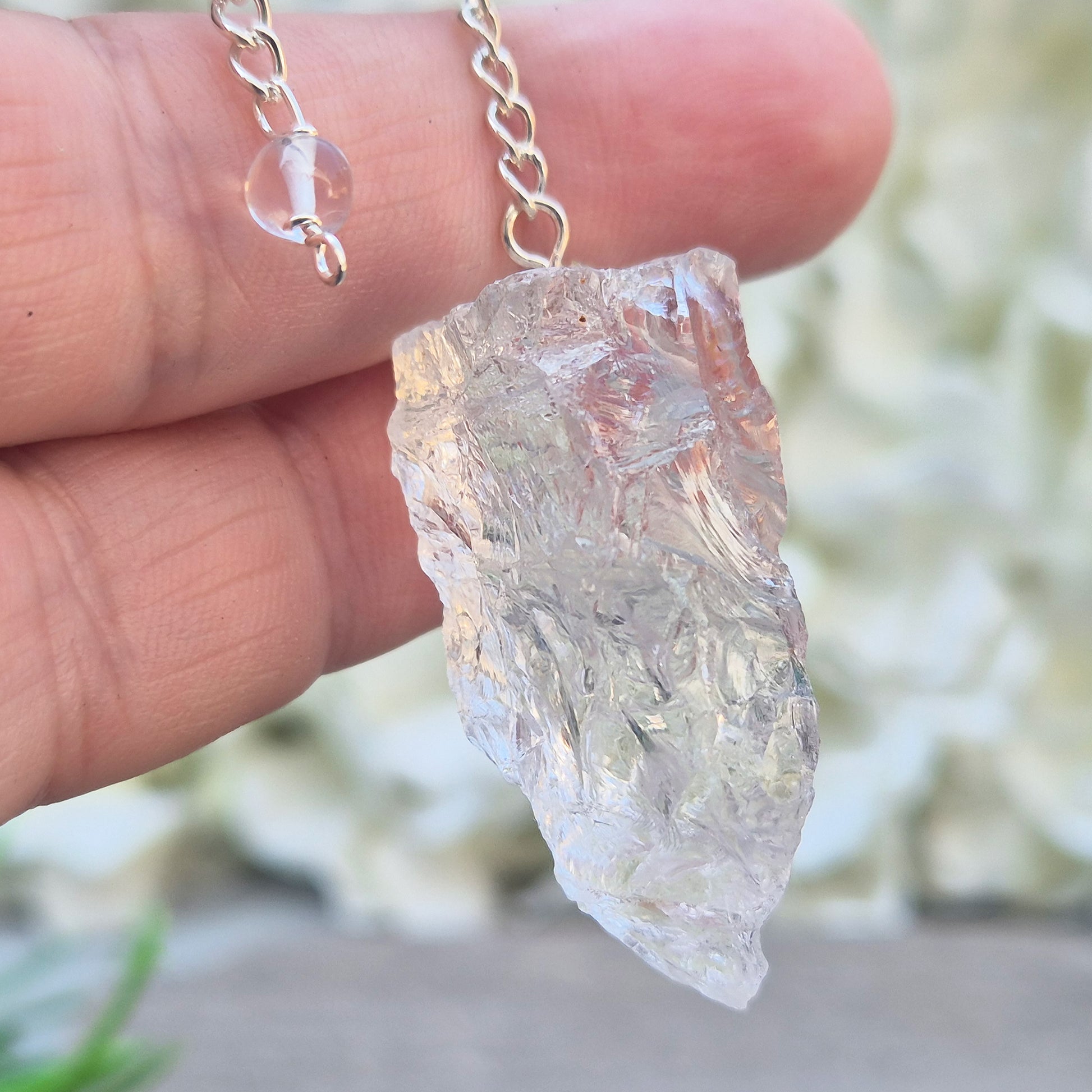 This Rock Quartz Crystal Pendulum from Brazil features a natural quartz crystal and a white bead at the end of the chain.&nbsp;It will come with a box or pouch for safe keeping. 
