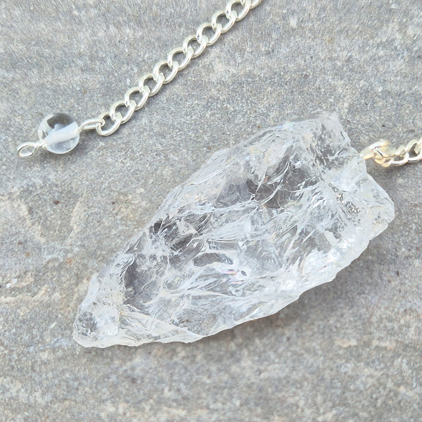 This Rock Quartz Crystal Pendulum from Brazil features a natural quartz crystal and a white bead at the end of the chain.&nbsp;It will come with a box or pouch for safe keeping. 