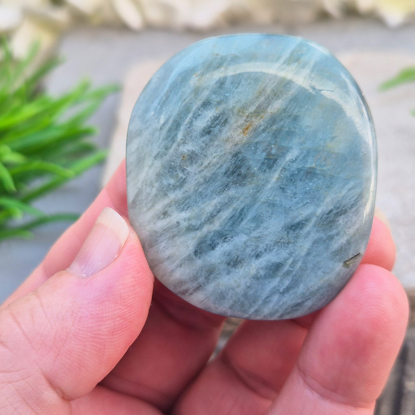 Aquamarine palm stone in pale aqua-blue, polished smooth. A calming crystal linked to the throat chakra, ideal for clearer thinking and honest conversations.