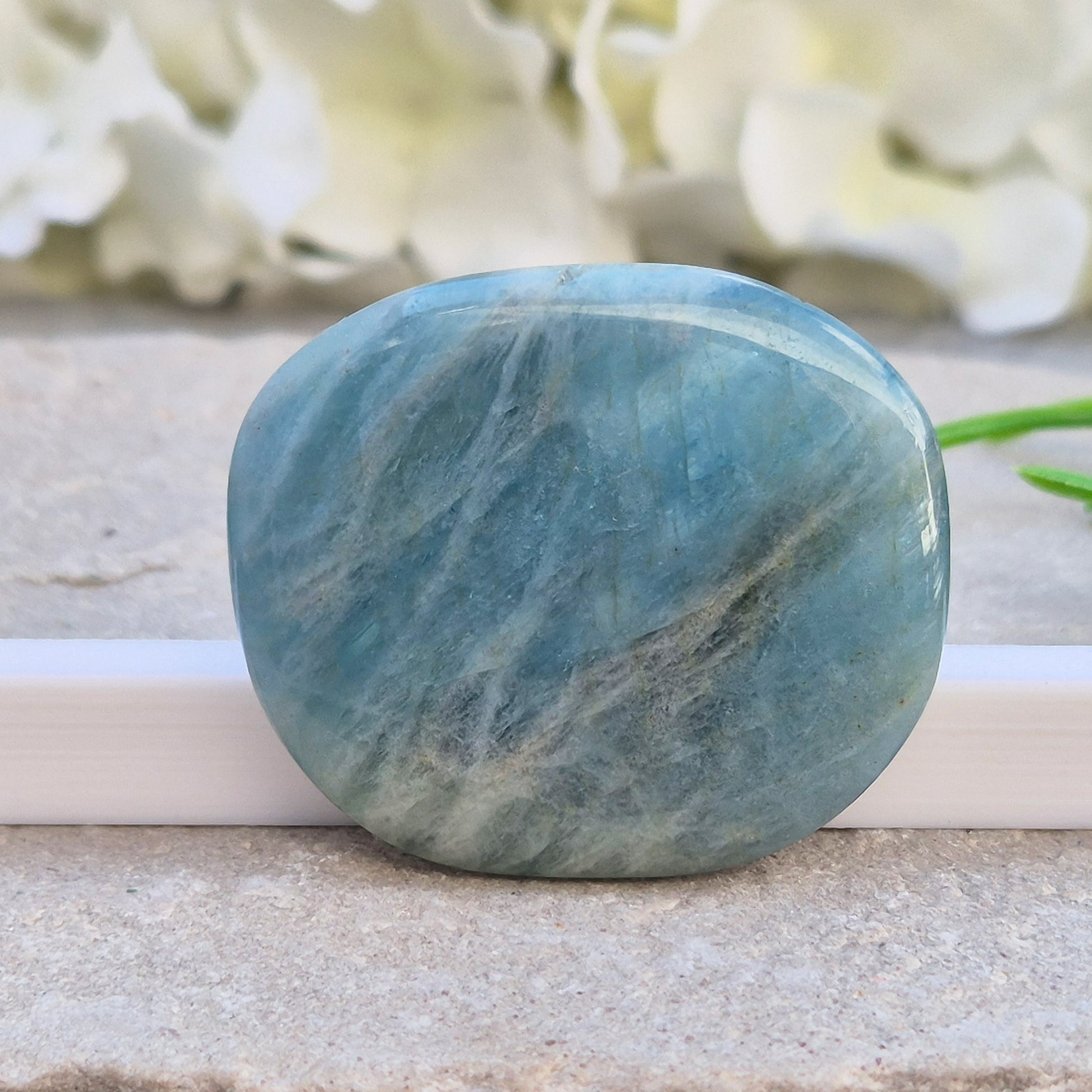 Aquamarine palm stone in pale aqua-blue, polished smooth. A calming crystal linked to the throat chakra, ideal for clearer thinking and honest conversations.