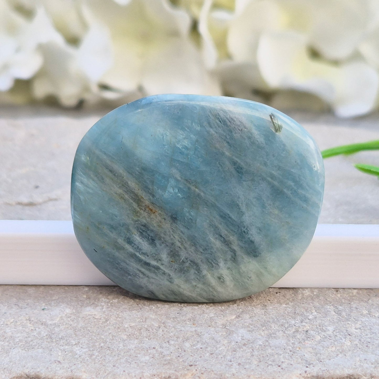Aquamarine palm stone in pale aqua-blue, polished smooth. A calming crystal linked to the throat chakra, ideal for clearer thinking and honest conversations.