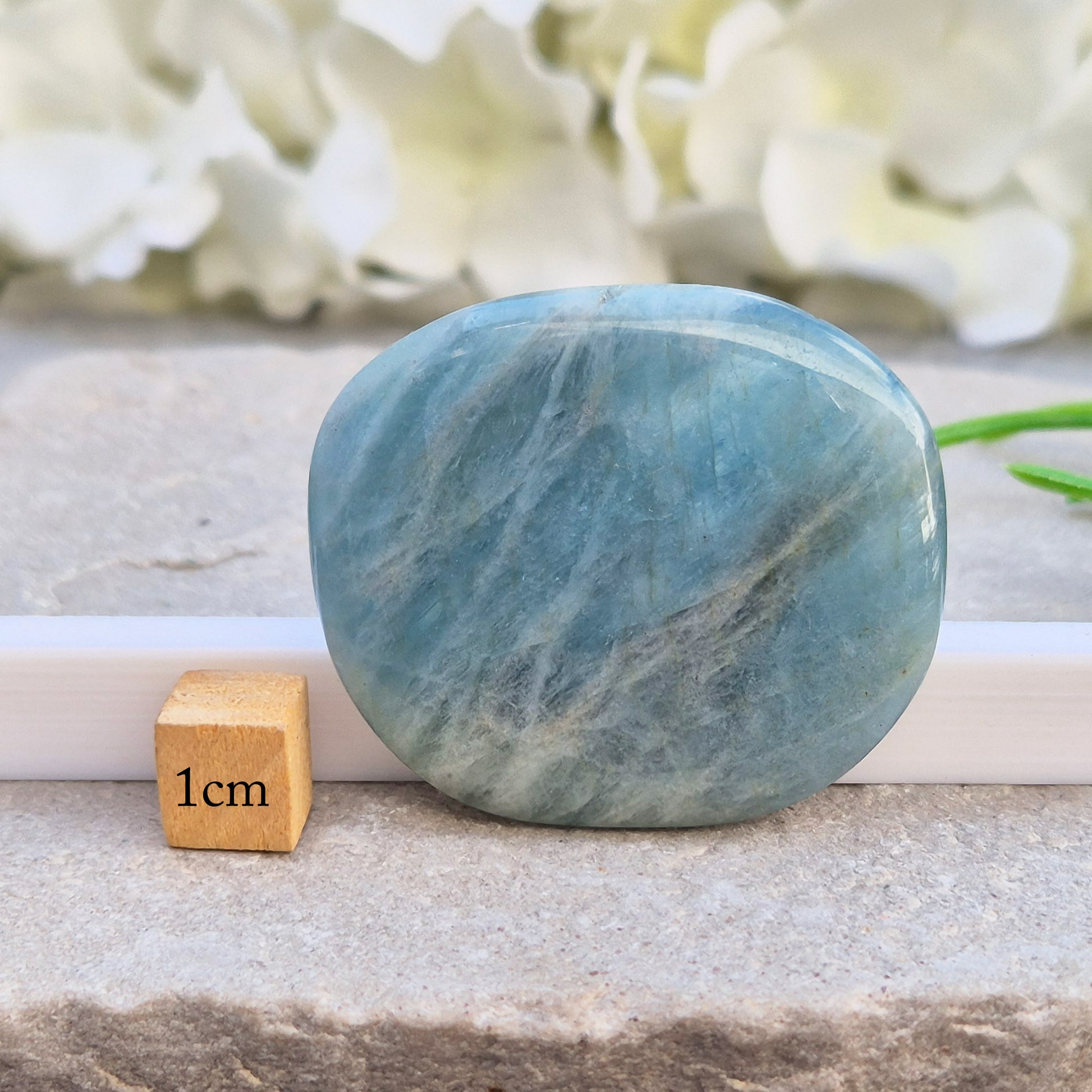 Aquamarine palm stone in pale aqua-blue, polished smooth. A calming crystal linked to the throat chakra, ideal for clearer thinking and honest conversations.