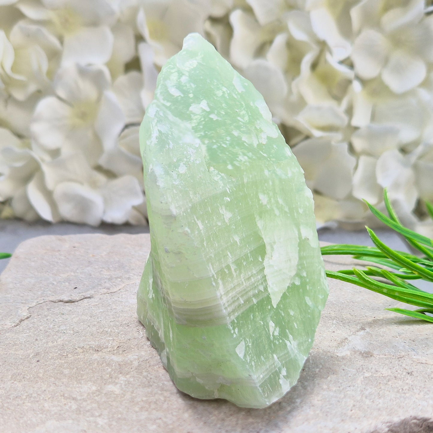 This natural self-standing Pistachio Calcite crystal comes from Pakistan and shows soft pale green to pistachio tones. This variety of Green Calcite gets its colouring from trace minerals embedded as the calcite formed.