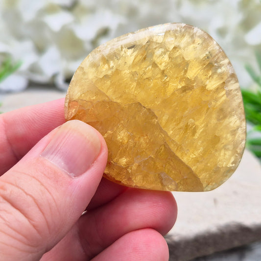 Honey Calcite Crystal Palm Stone, sometimes refered to as Golden Calcite or Amber Calcite. A smooth, pocket-sized palm stone in warm honey-gold tones, ranging from pale lemon-yellow to deep amber.