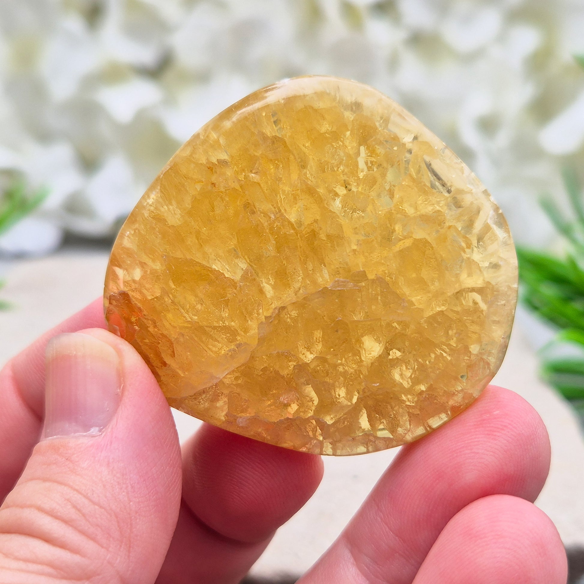 Honey Calcite Crystal Palm Stone, sometimes refered to as Golden Calcite or Amber Calcite. A smooth, pocket-sized palm stone in warm honey-gold tones, ranging from pale lemon-yellow to deep amber.