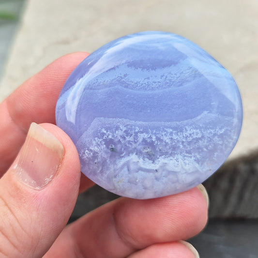 Polished Blue Lace Agate palm stone from Namibia. Often associated with calm communication and easing emotional tension, with soft blue banding throughout.