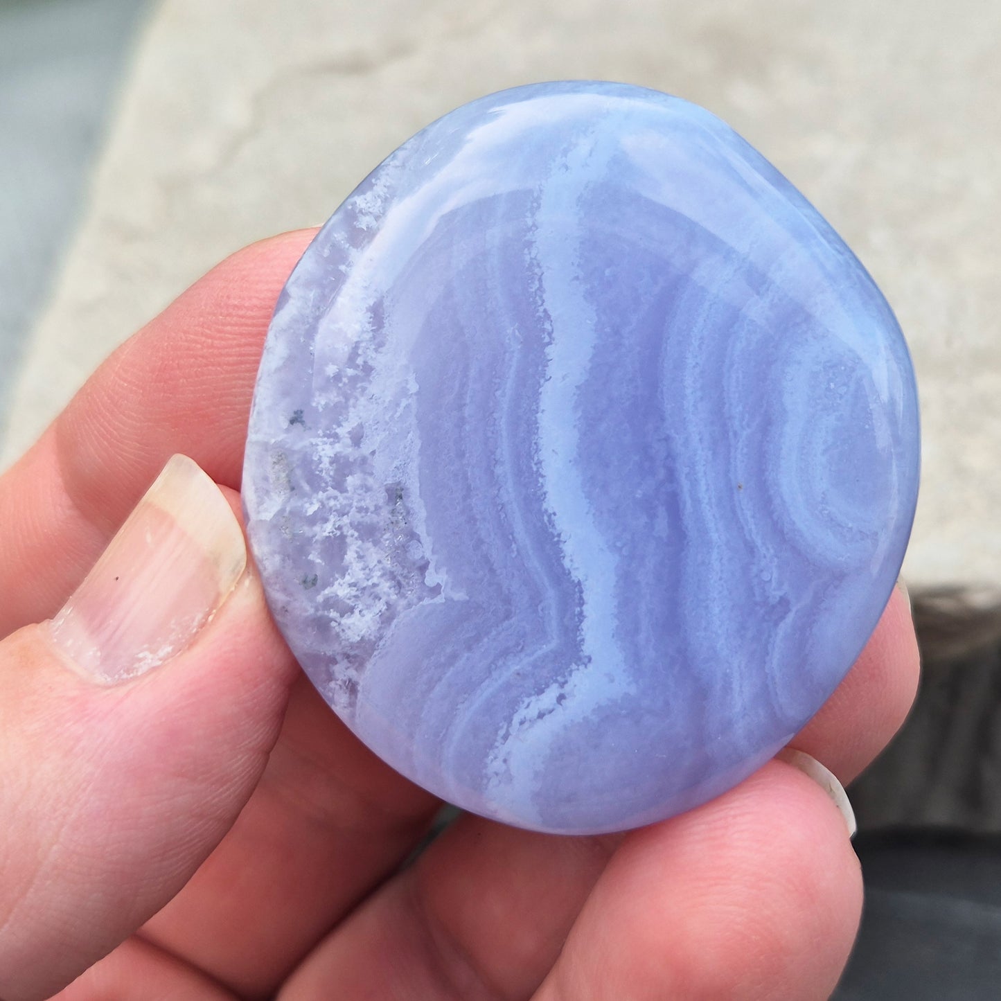 Polished Blue Lace Agate palm stone from Namibia. Often associated with calm communication and easing emotional tension, with soft blue banding throughout.