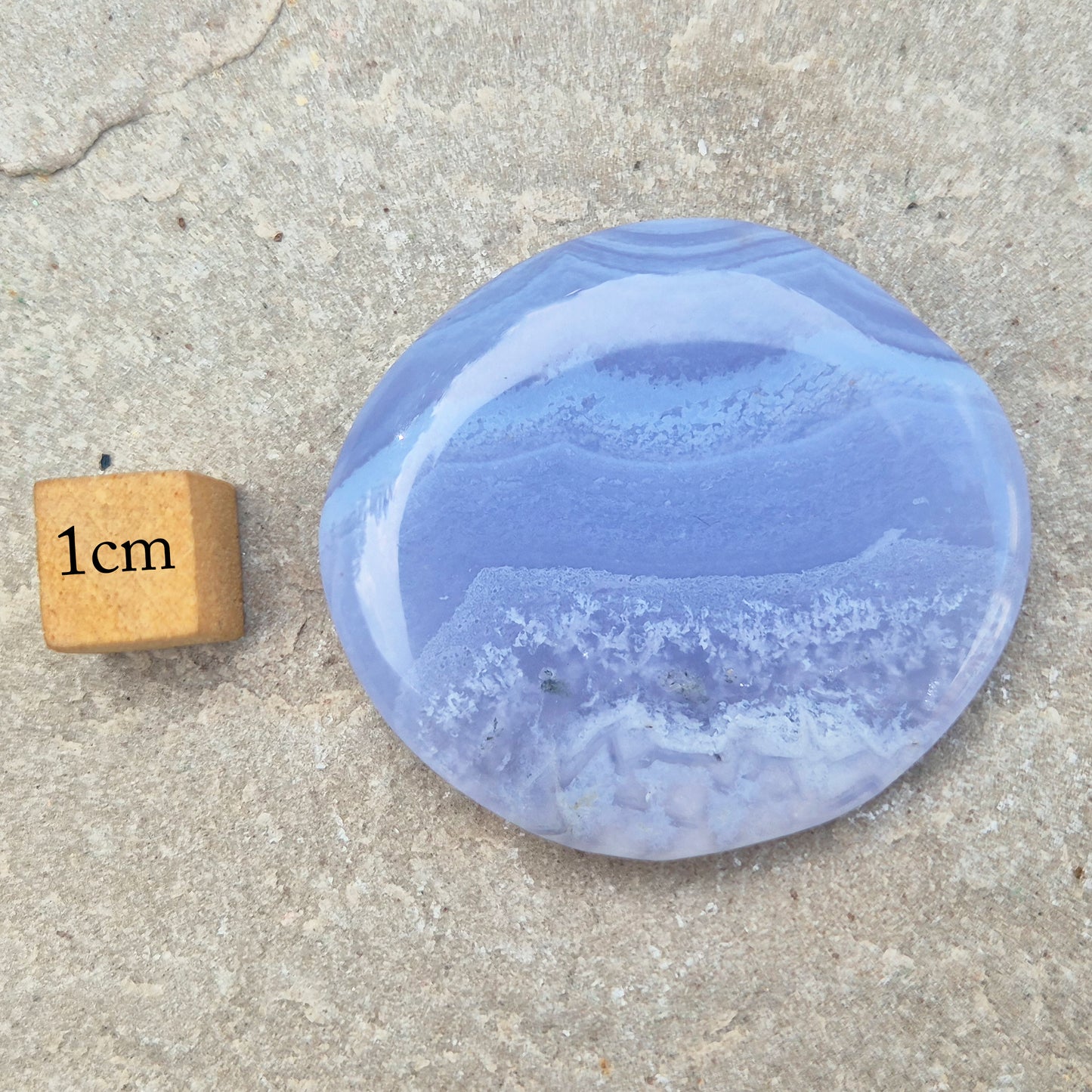 Polished Blue Lace Agate palm stone from Namibia. Often associated with calm communication and easing emotional tension, with soft blue banding throughout.
