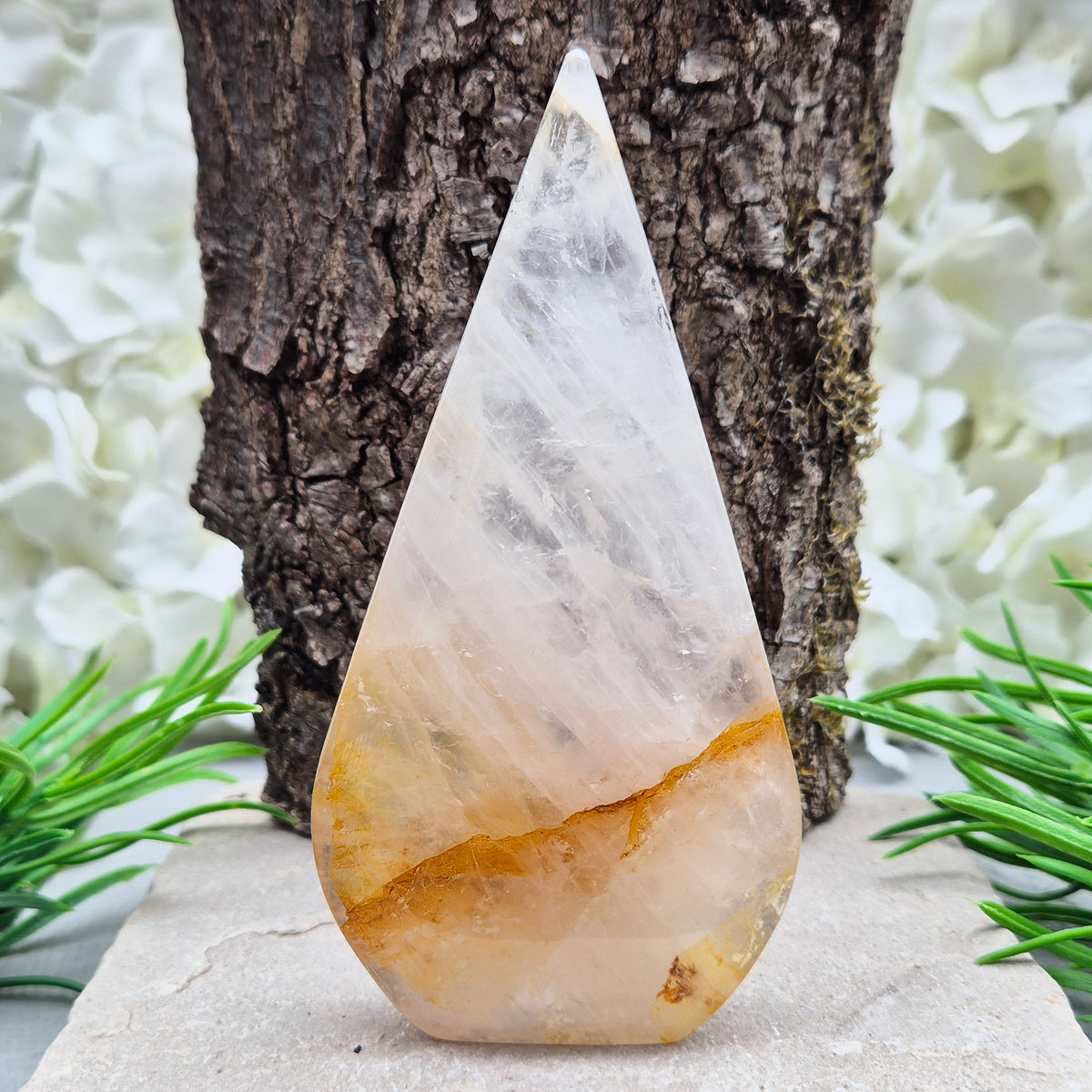 This Golden Healer Quartz teardrop is polished from Brazilian quartz, threaded through with golden inclusions of iron oxide inclusions (also known in the trade as yellow hematoid quartz). The smooth teardrop shape tapers to a clean point, standing upright on its own, with the golden banding visible right through the stone.