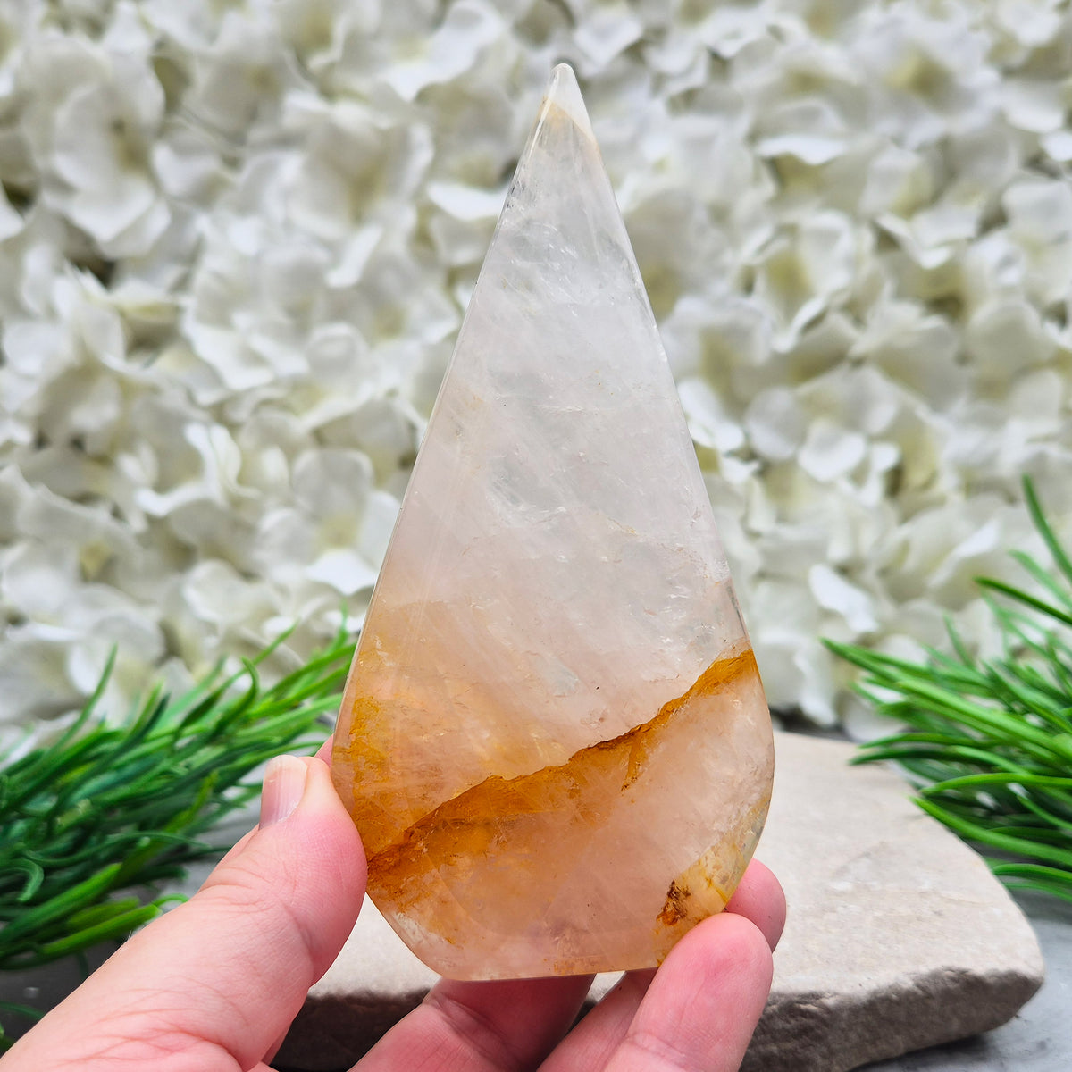 This Golden Healer Quartz teardrop is polished from Brazilian quartz, threaded through with golden inclusions of iron oxide inclusions (also known in the trade as yellow hematoid quartz). The smooth teardrop shape tapers to a clean point, standing upright on its own, with the golden banding visible right through the stone.