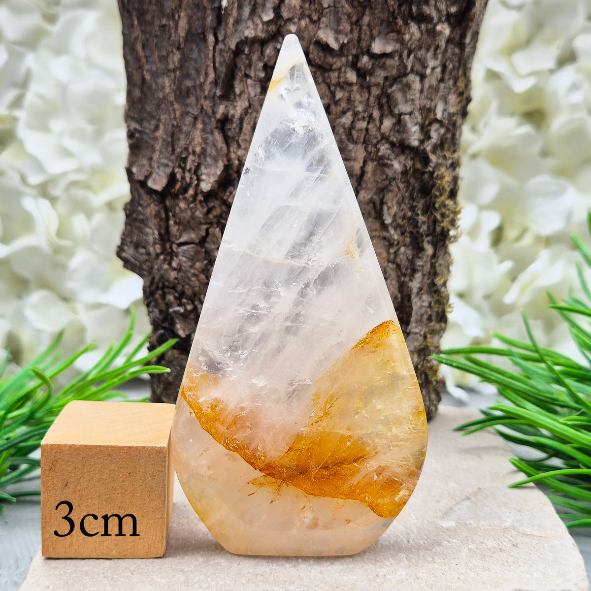 This Golden Healer Quartz teardrop is polished from Brazilian quartz, threaded through with golden inclusions of iron oxide inclusions (also known in the trade as yellow hematoid quartz). The smooth teardrop shape tapers to a clean point, standing upright on its own, with the golden banding visible right through the stone.