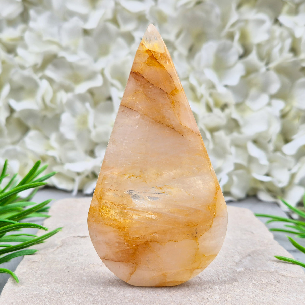 This Golden Healer Quartz teardrop is polished from Brazilian quartz, threaded through with golden inclusions of iron oxide inclusions (also known in the trade as yellow hematoid quartz). The smooth teardrop shape tapers to a clean point, standing upright on its own, with the golden banding visible right through the stone.