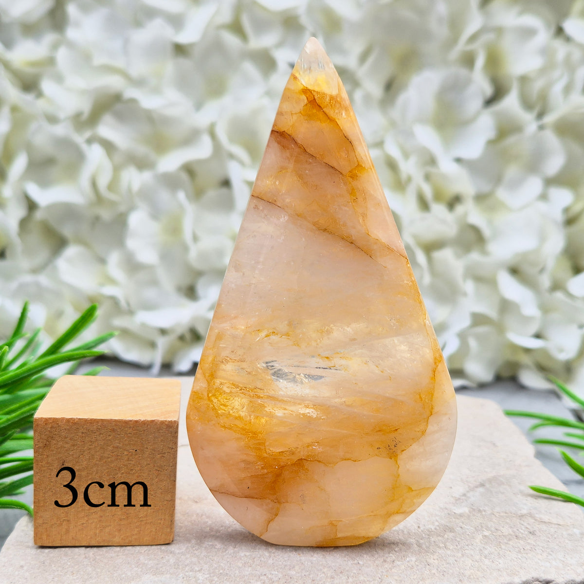 This Golden Healer Quartz teardrop is polished from Brazilian quartz, threaded through with golden inclusions of iron oxide inclusions (also known in the trade as yellow hematoid quartz). The smooth teardrop shape tapers to a clean point, standing upright on its own, with the golden banding visible right through the stone.