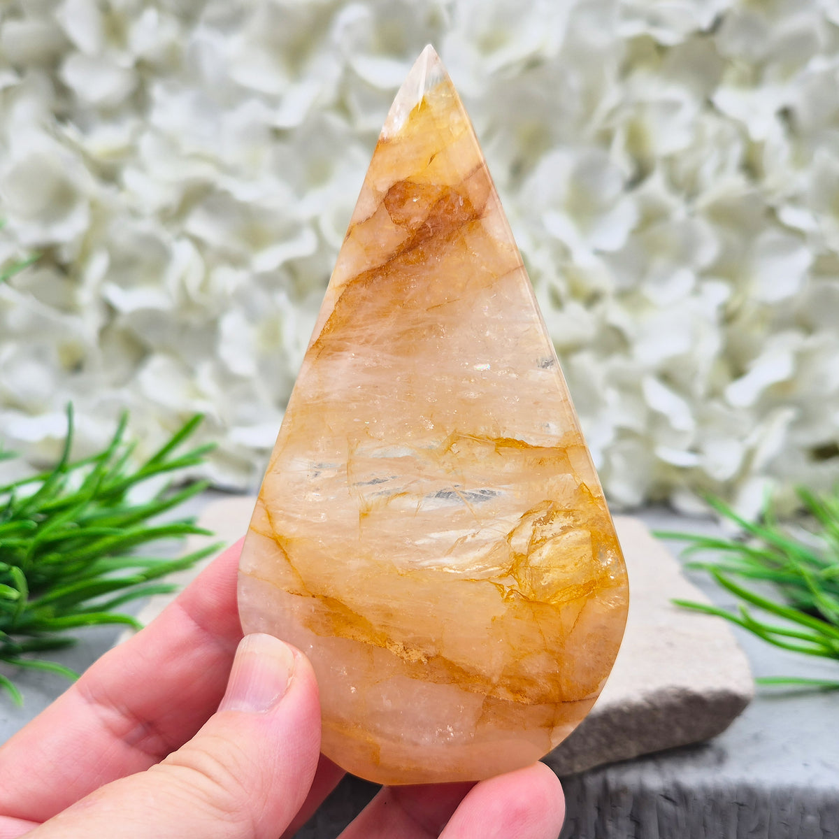 This Golden Healer Quartz teardrop is polished from Brazilian quartz, threaded through with golden inclusions of iron oxide inclusions (also known in the trade as yellow hematoid quartz). The smooth teardrop shape tapers to a clean point, standing upright on its own, with the golden banding visible right through the stone.