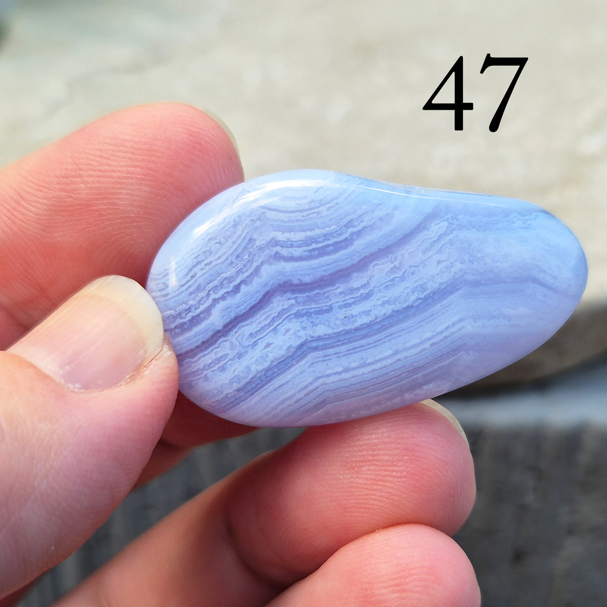 Polished Blue Lace Agate palm stone from Namibia. Often associated with calm communication and easing emotional tension, with soft blue banding throughout.