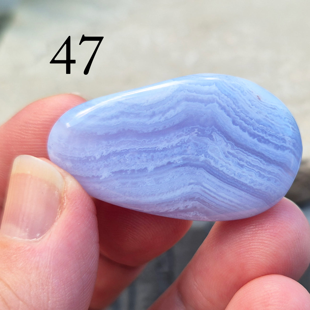 Polished Blue Lace Agate palm stone from Namibia. Often associated with calm communication and easing emotional tension, with soft blue banding throughout.